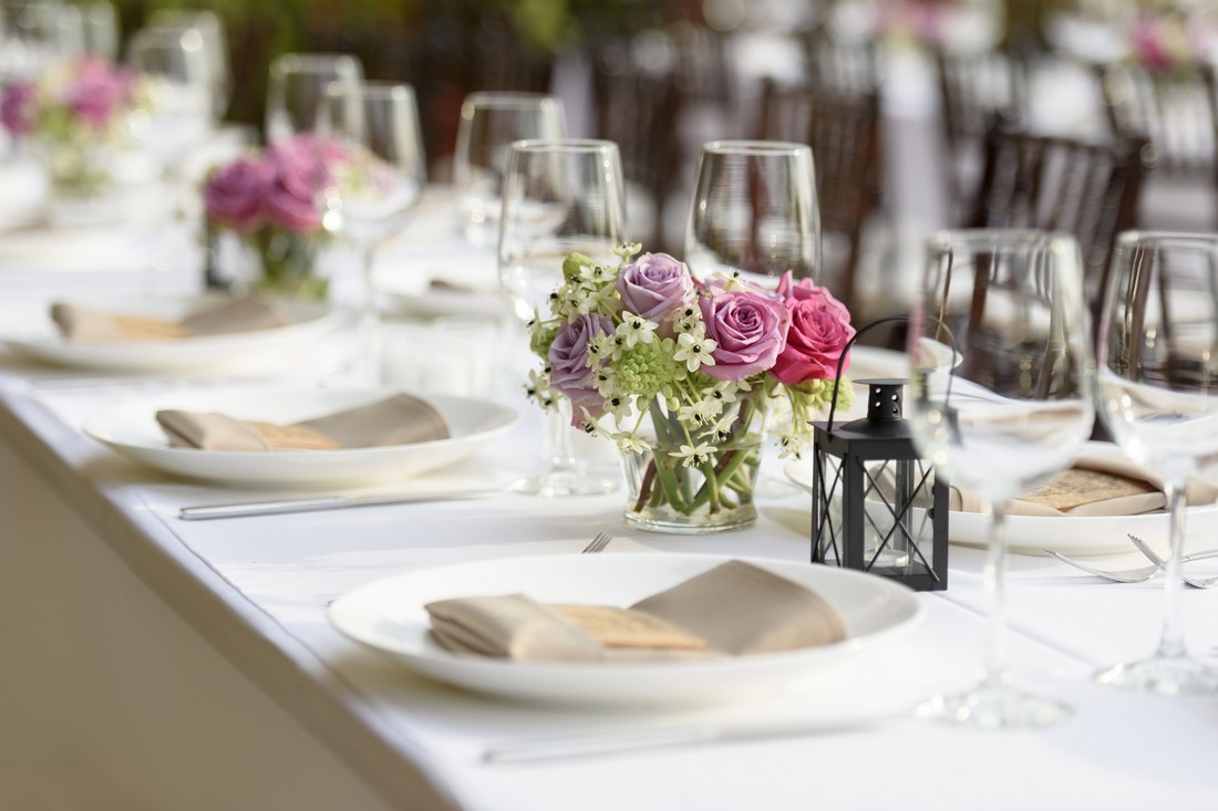Long table setting with small flower arrangements as centerpieces.